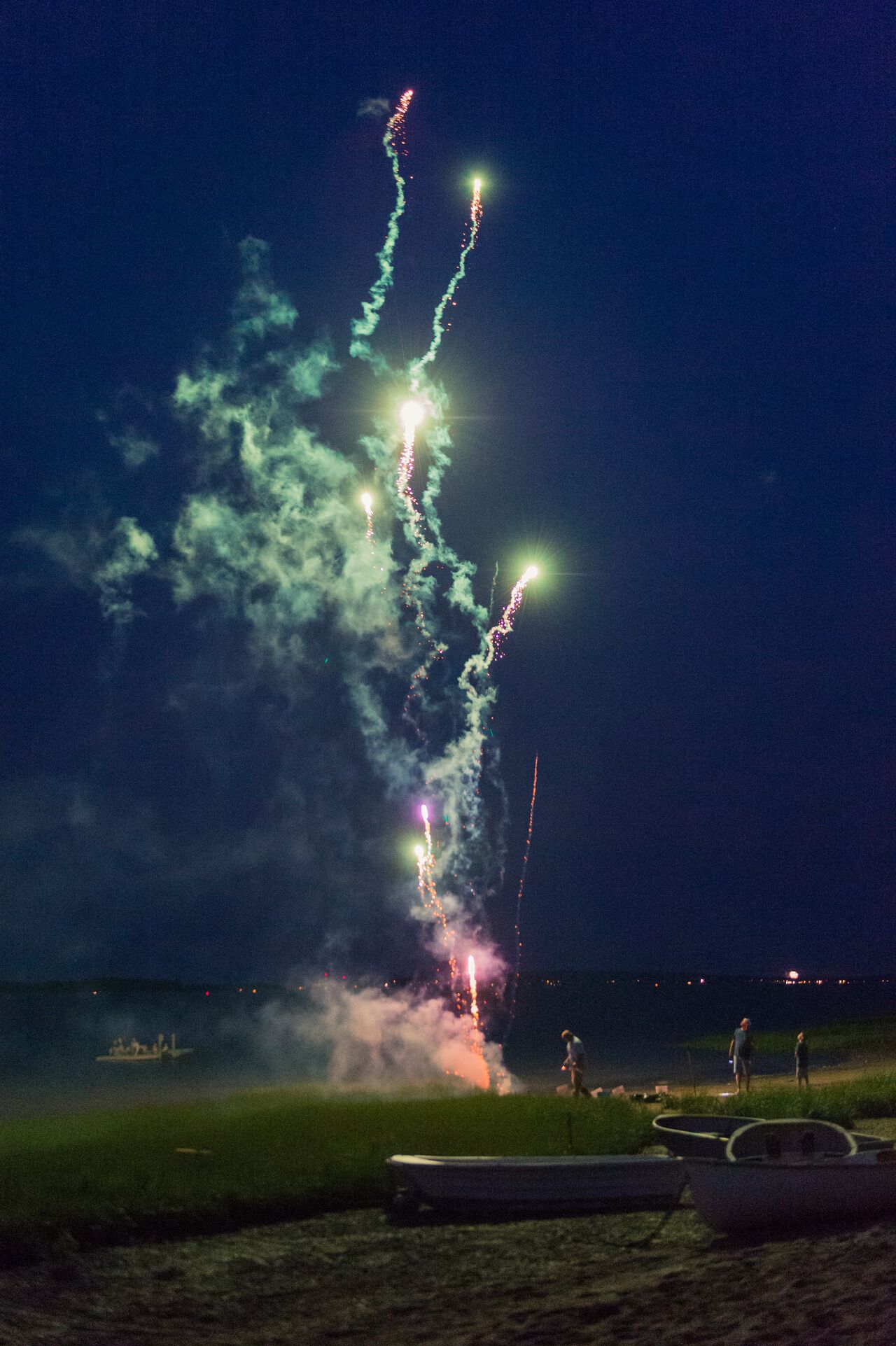 Fireworks light up the night sky on the beach as people watch during a 4th of July celebration.