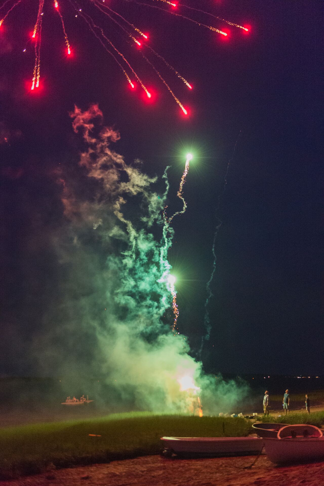Fireworks light up the night sky on the beach as people watch during a 4th of July celebration.