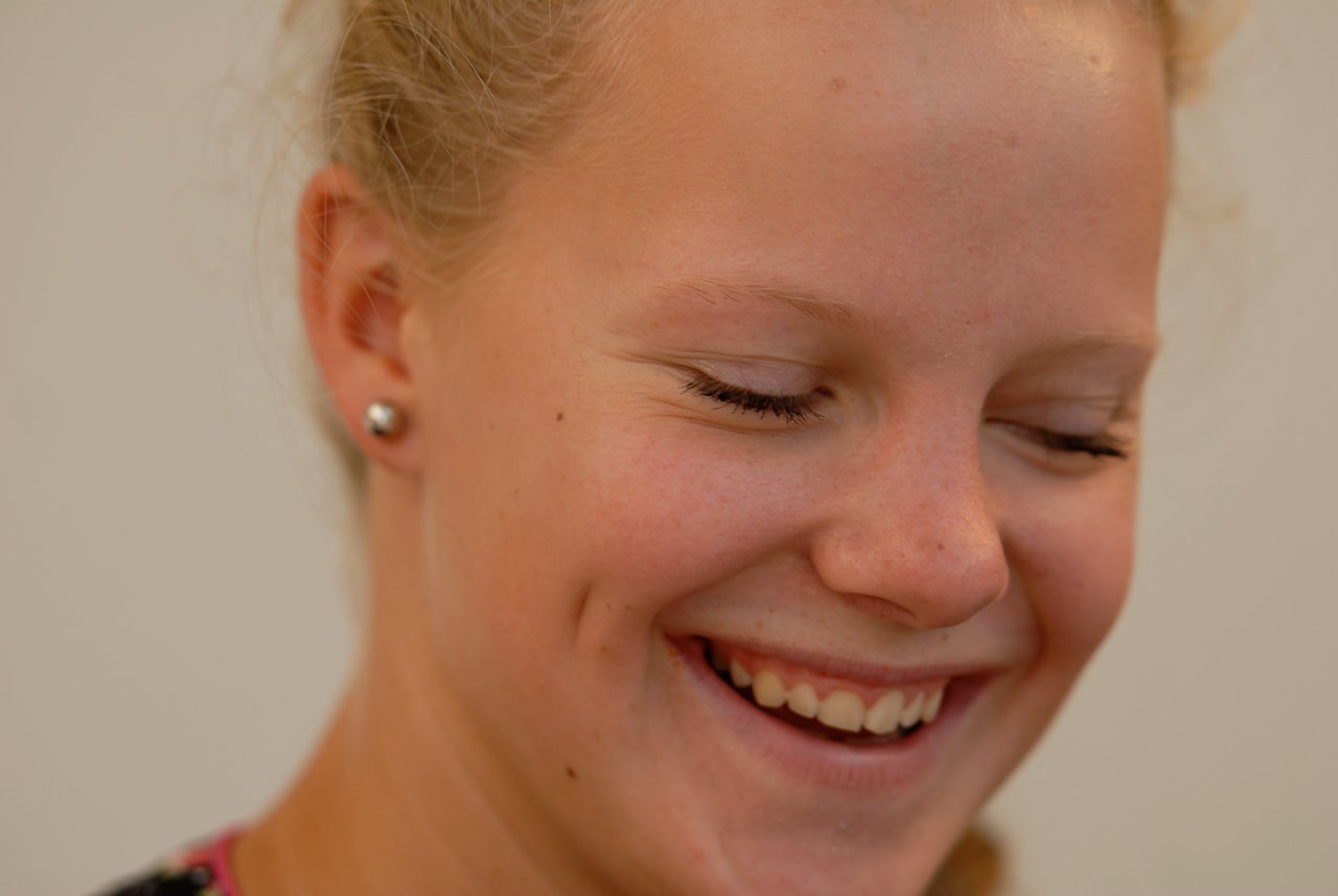 A young woman smiles with her eyes closed, appearing happy at the party.