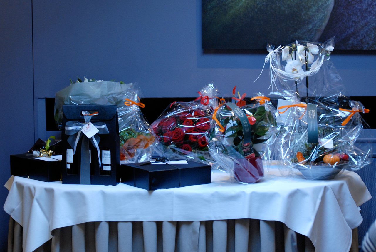 A table with wrapped gifts, flowers, and wine bottles, prepared for a 60th-anniversary celebration.