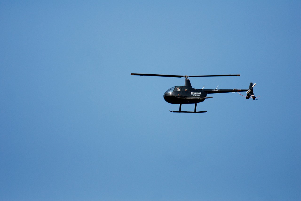 A black helicopter flies in a clear blue sky, possibly related to the anniversary party event.