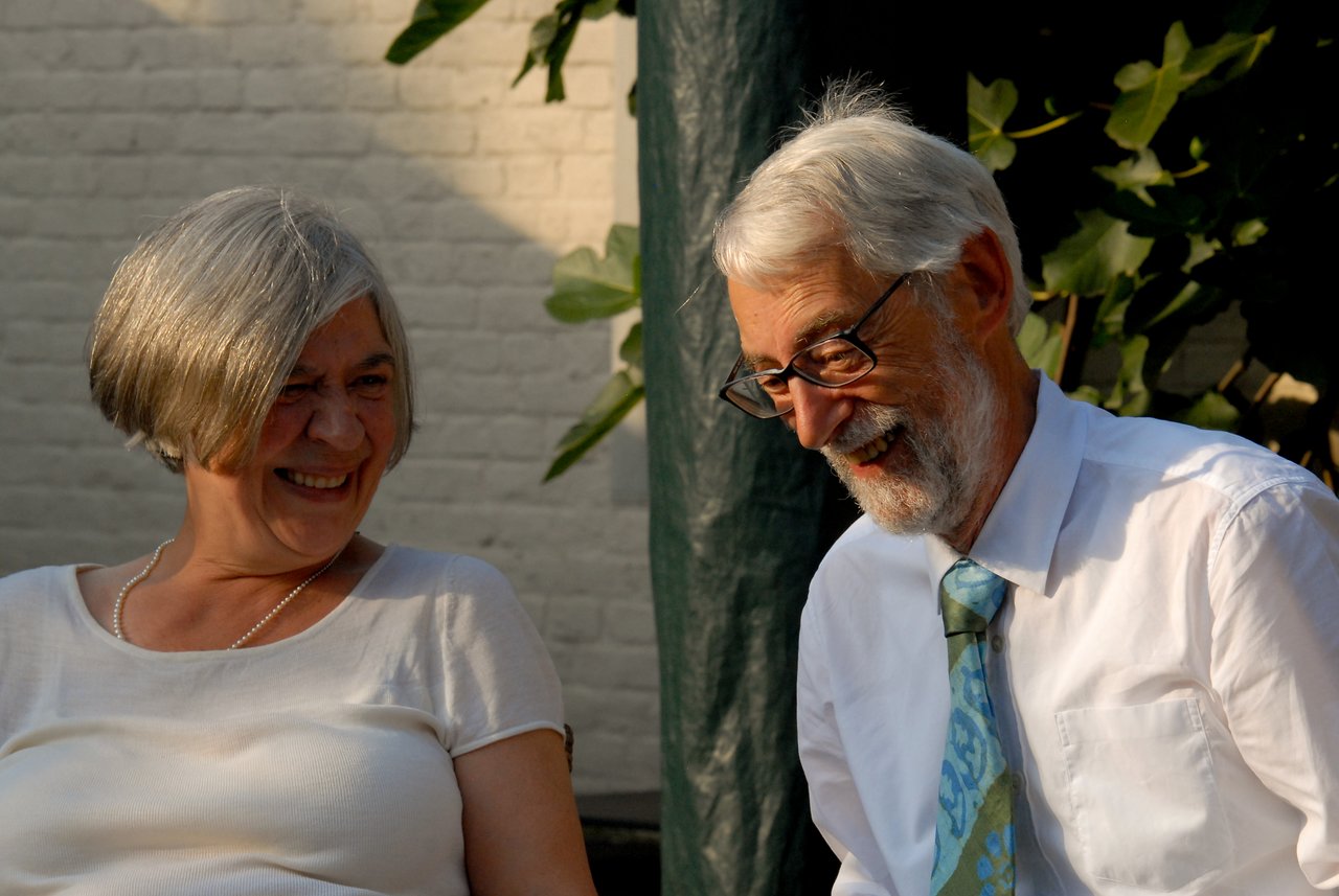 An older couple sits together, smiling and laughing during a celebration.