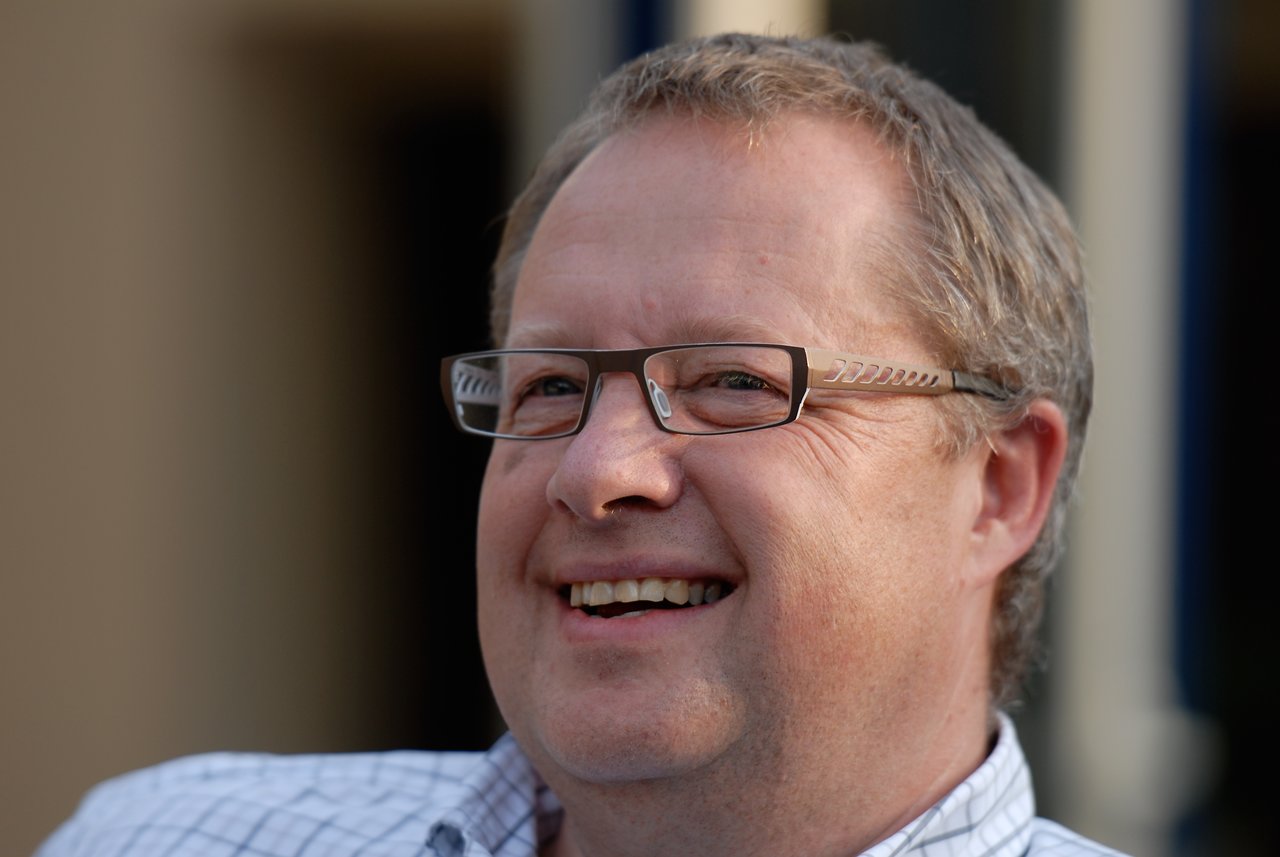 A man wearing glasses and a checkered shirt smiles while enjoying the party.