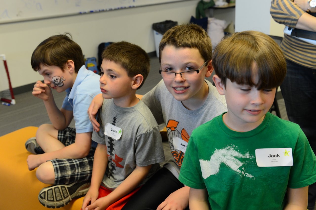 Four children sit together, with one smiling at the camera and another with a face painting.