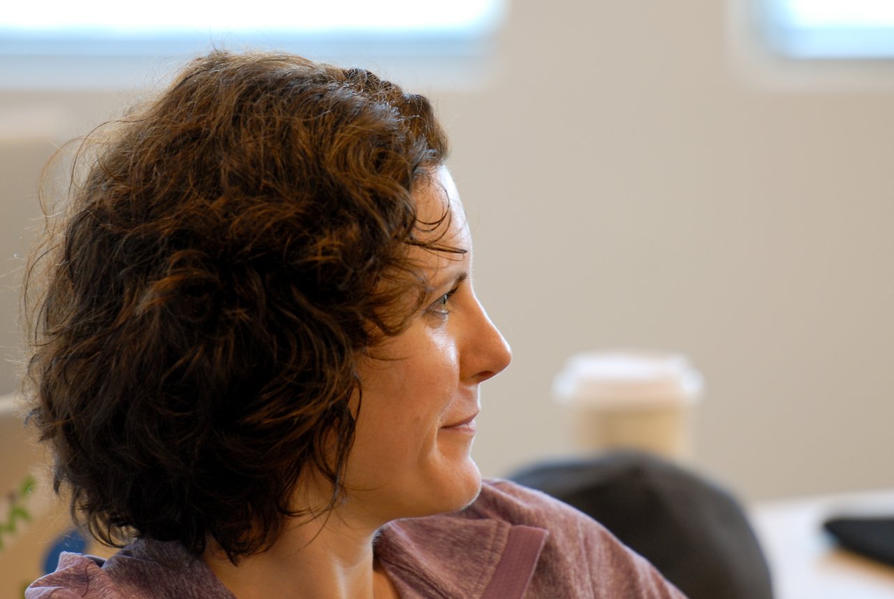 A person with short, curly hair listens attentively during a meeting or discussion.