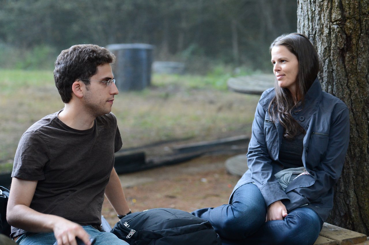 Two people sitting outdoors, engaged in conversation.