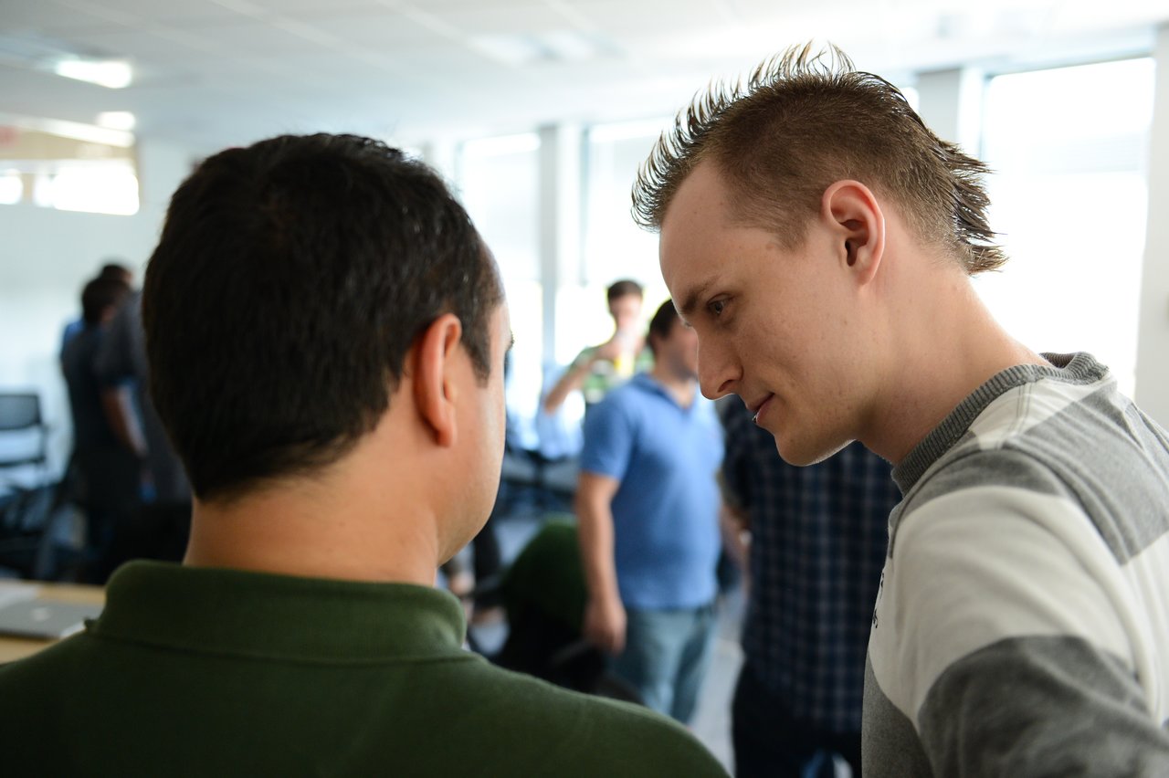 Two people in conversation, one leaning in while the other listens.