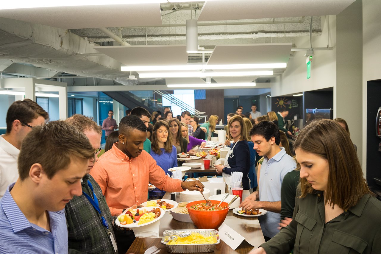 A group of people serving themselves food from a buffet table at a professional networking event.