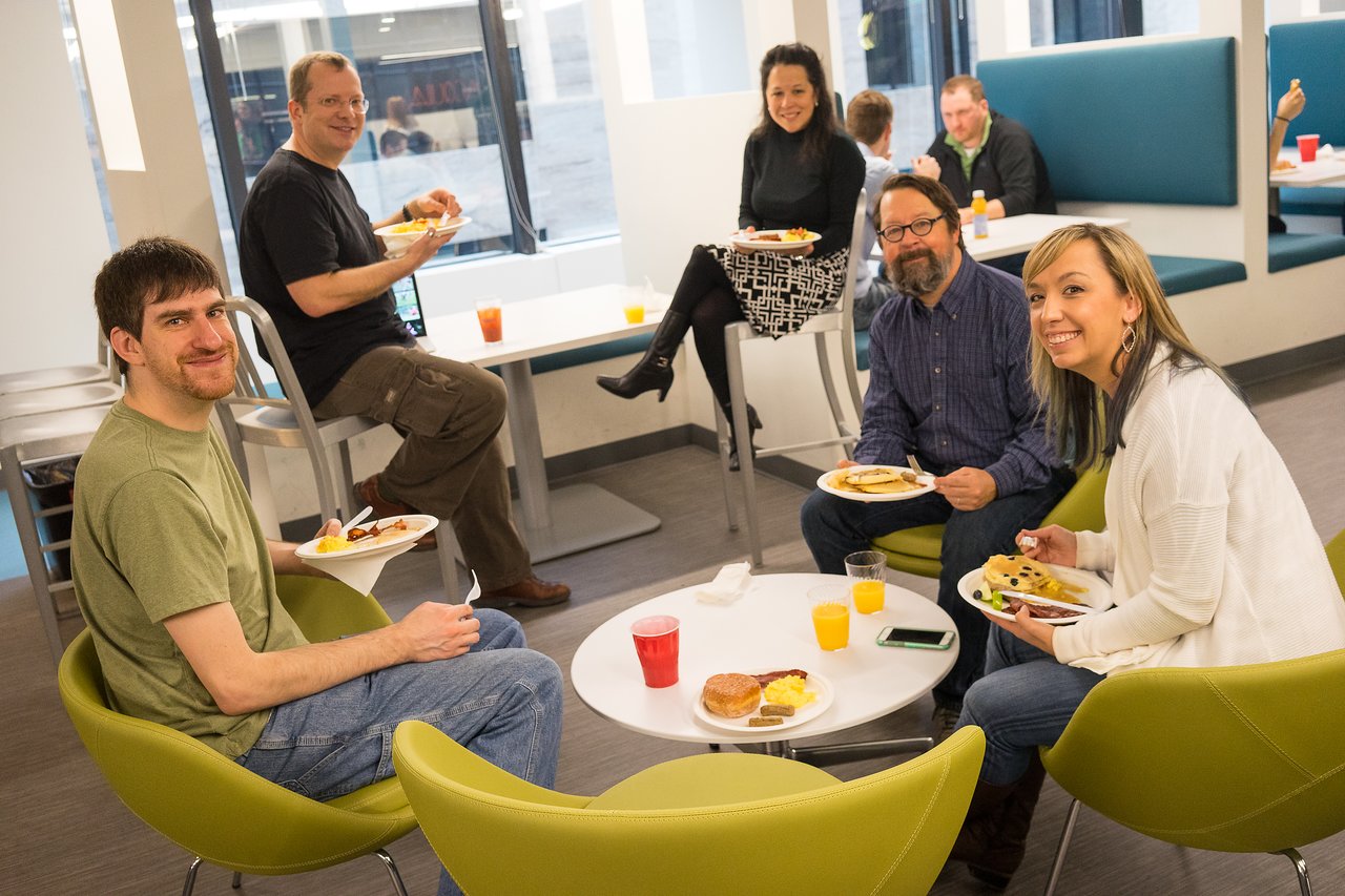 A group of people enjoying breakfast together at an Acquia event, smiling and engaging in conversation.