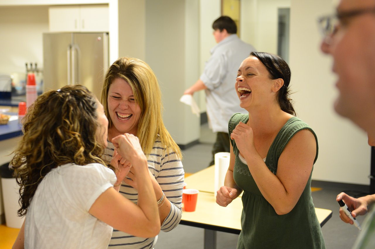 Three women laughing and chatting together at a party, appearing to enjoy the moment.