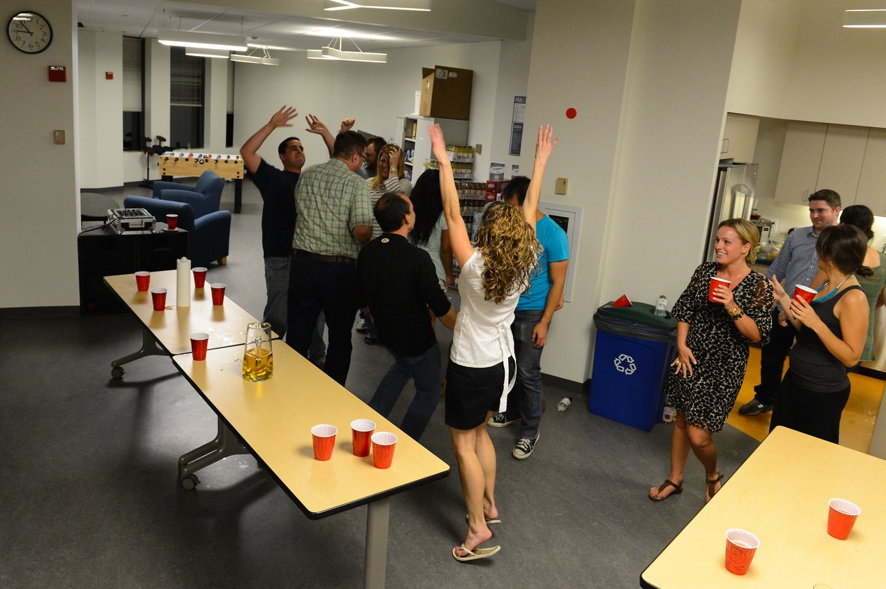 A group of people at a party, some raising their hands and others holding red cups, enjoying the moment.