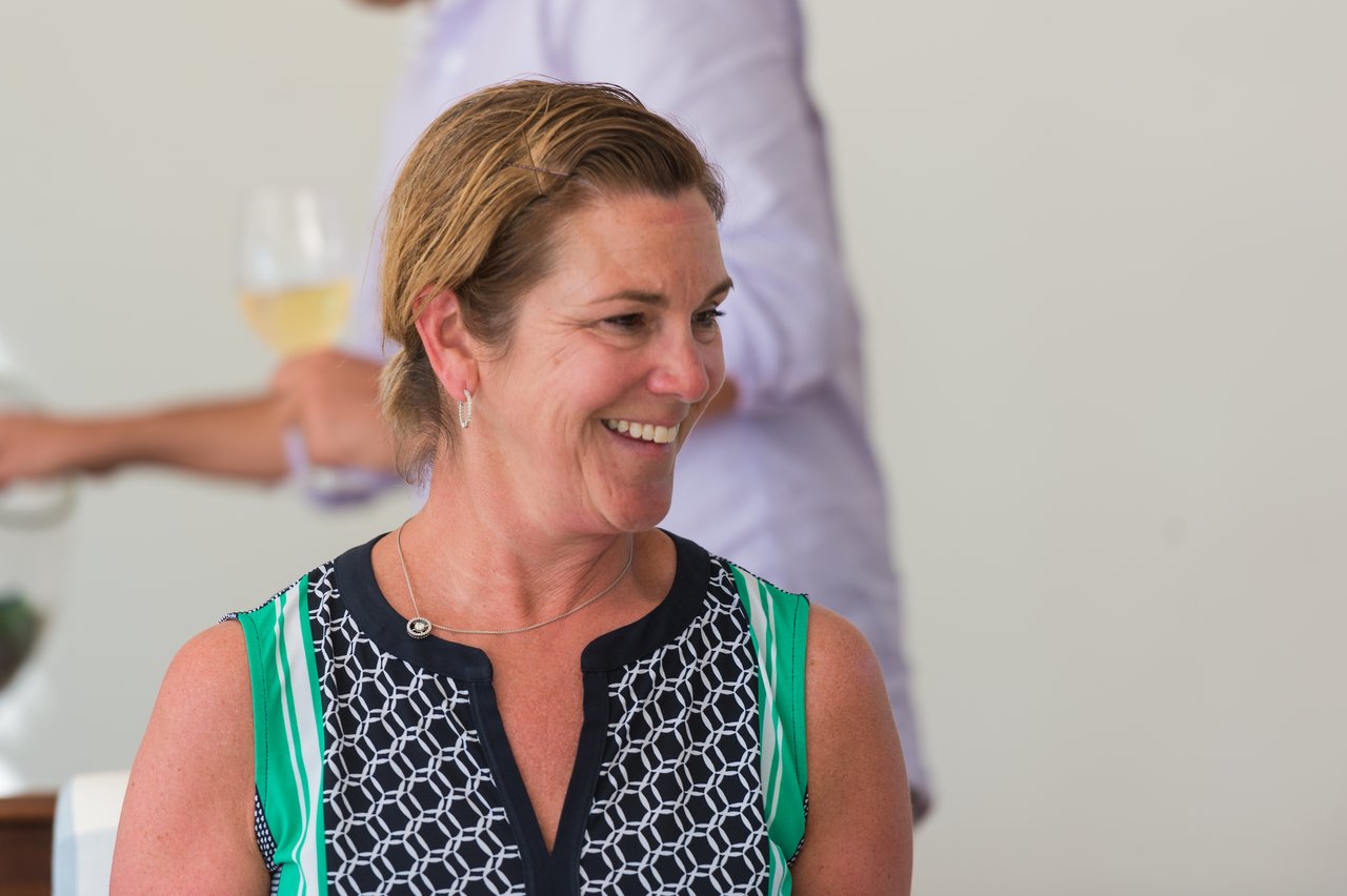 A woman smiles while engaged in conversation at an offsite event.