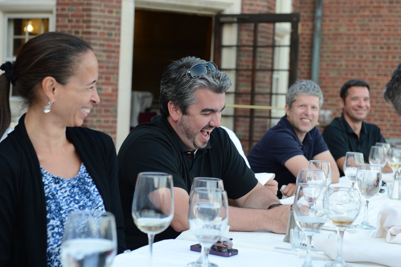 A group of people sitting at a dinner table, laughing and enjoying a conversation.