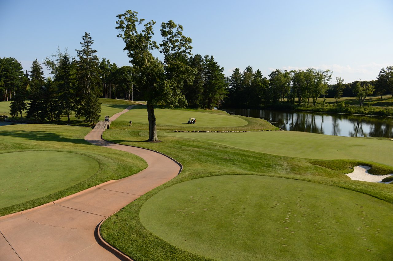A golf course with a winding path, a small bridge, and a pond.