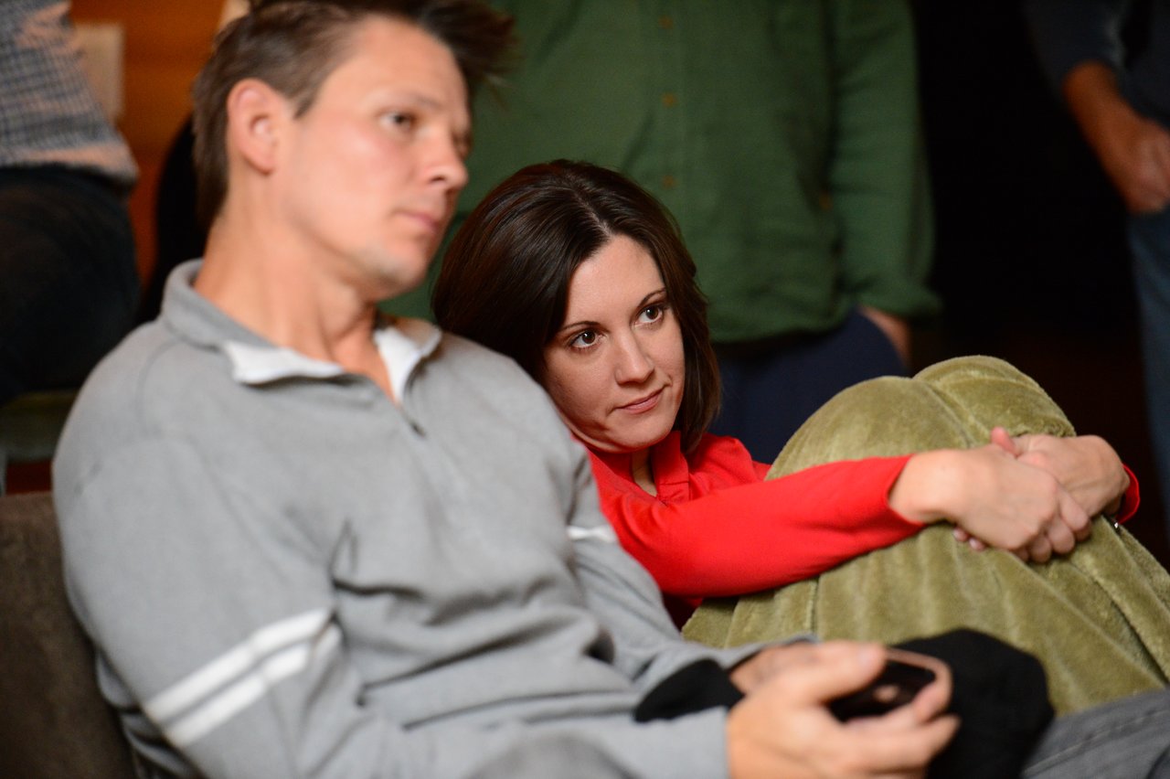 Two people sit closely together, watching something off-camera.