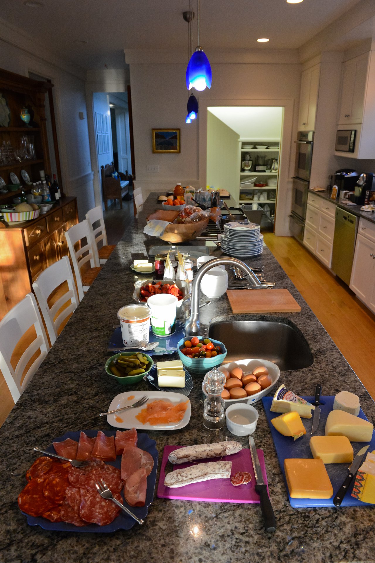 A kitchen island filled with meats, cheeses, eggs, and other food items, prepared for a gathering or meal.