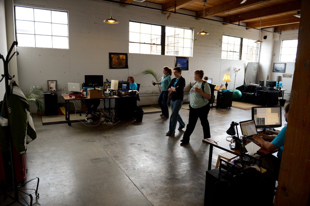 An open office space with employees working at desks and a group walking through the room.