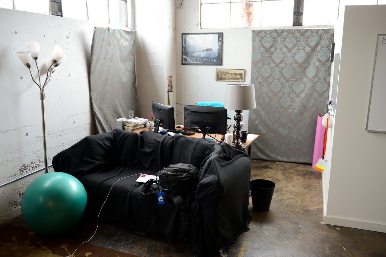 A workspace with a desk, computer, and couch in an industrial-style office with minimal decor.