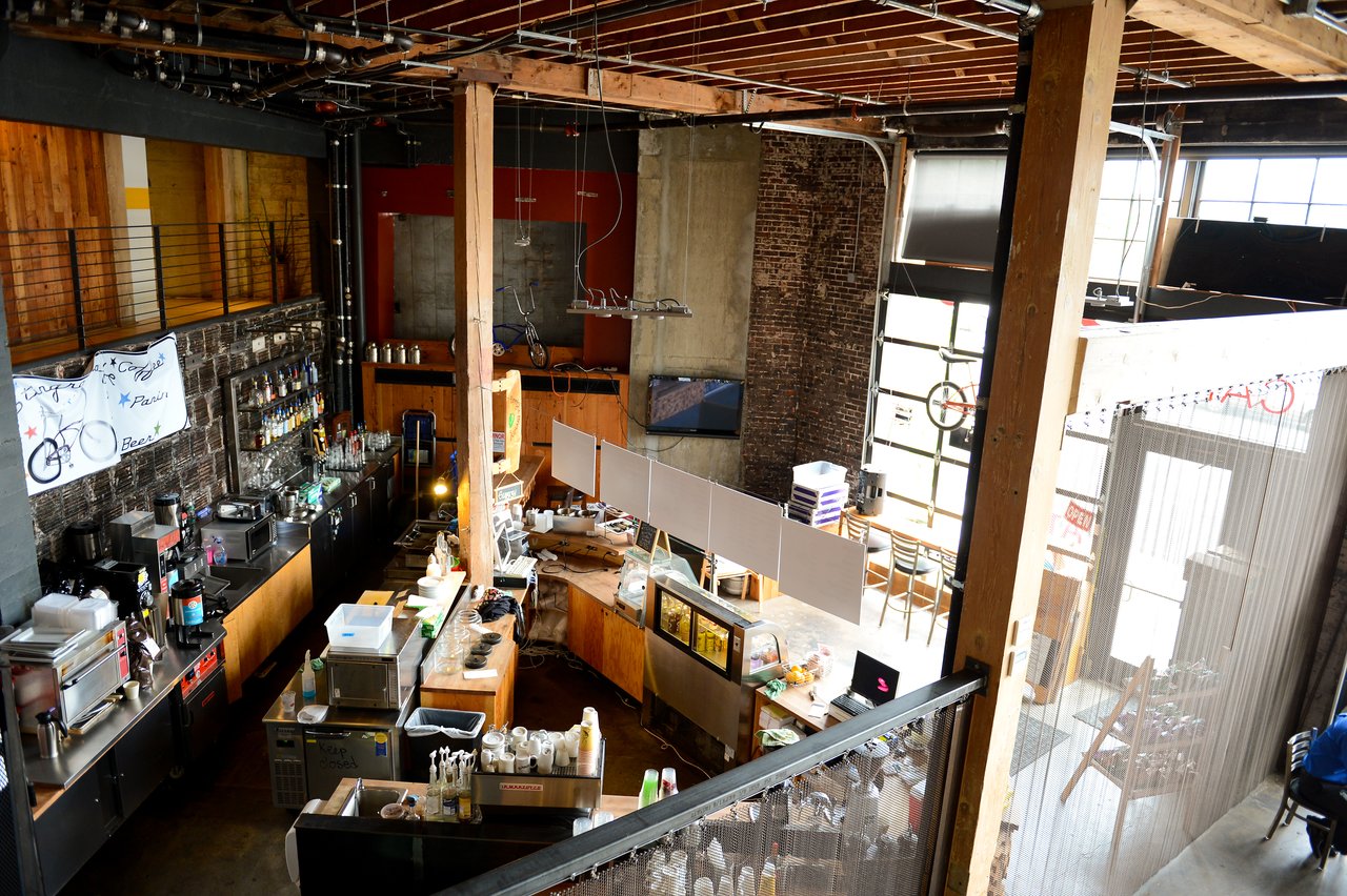 Open-concept office space with a bar area, wooden beams, and industrial design elements.