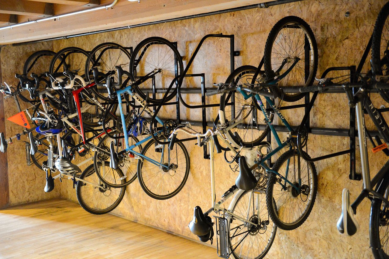 Several bicycles are hanging on a wall-mounted rack in an office bike storage area.