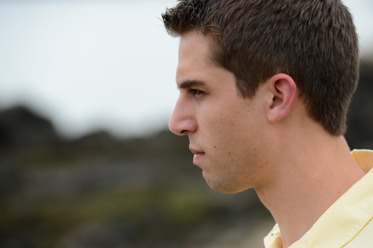 A person in a yellow shirt looks to the side with a serious expression.