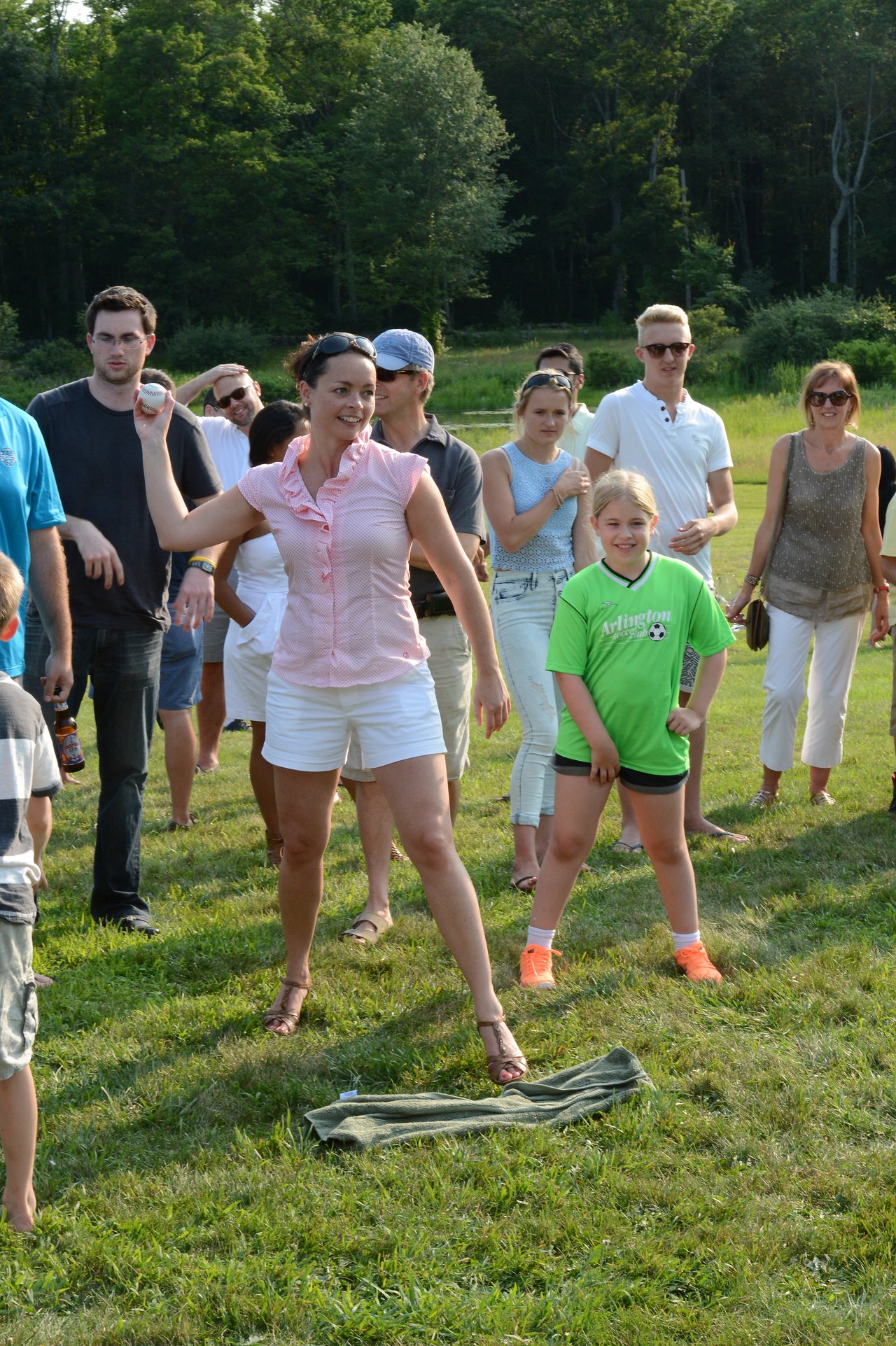 A woman prepares to throw a ball at a dunk tank target while a crowd watches.