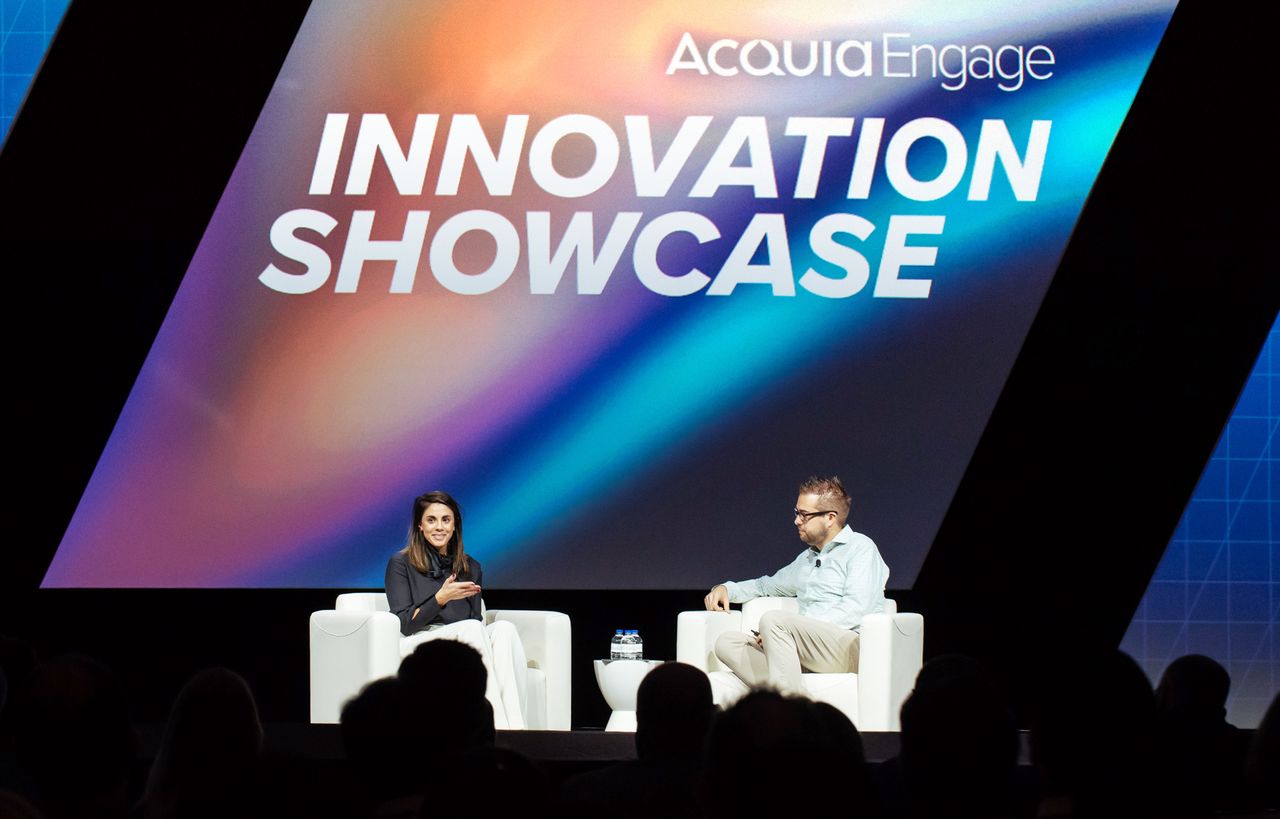 Two people sit on stage discussing innovation at Acquia Engage's Innovation Showcase event.