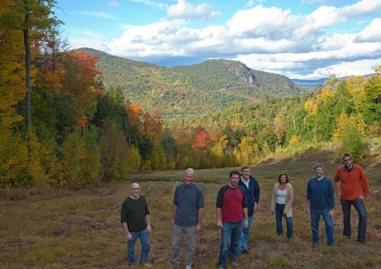 A group of seven Acquia leadership team members standing together outdoors, facing the camera.