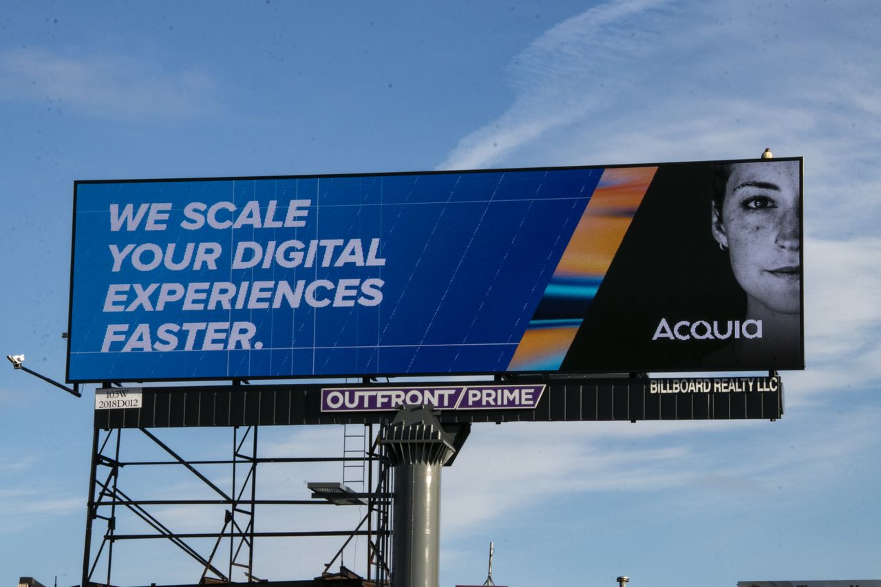 A billboard displays the text "We scale your digital experiences faster.