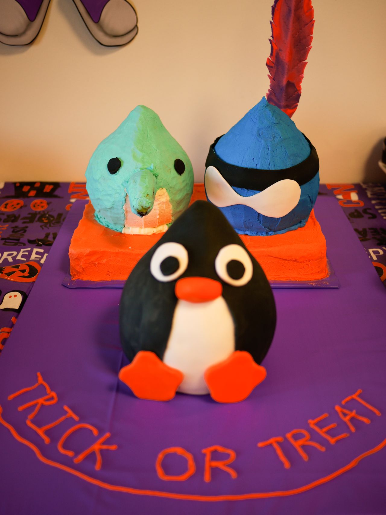 Three character-shaped cakes sit on a Halloween table with "Trick or Treat" written in icing.