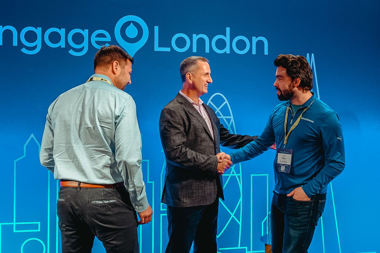 Steve Reny shakes hands with a partner on stage at Acquia Engage London.
