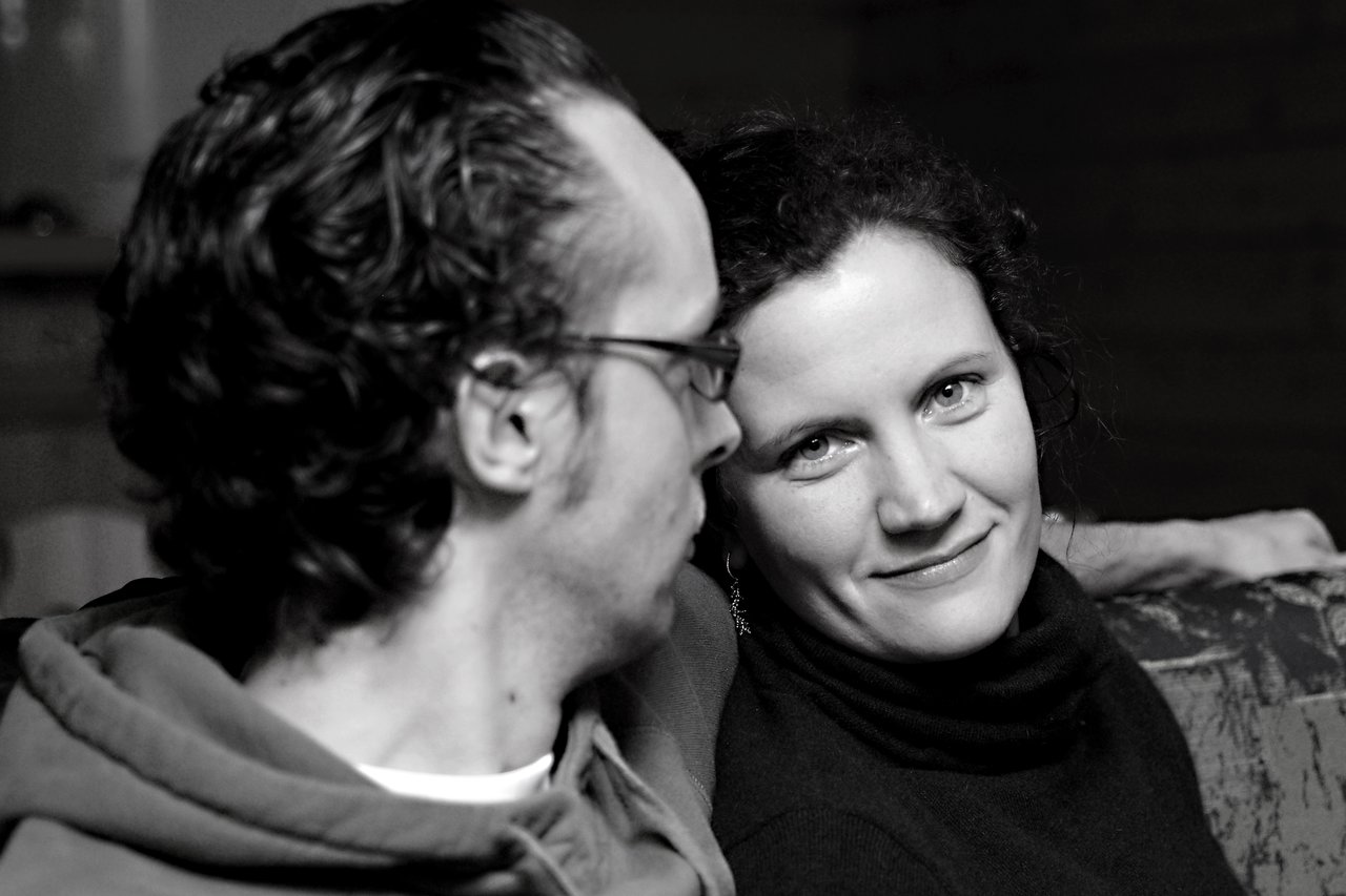 A woman smiles at the camera while a man beside her looks in her direction.