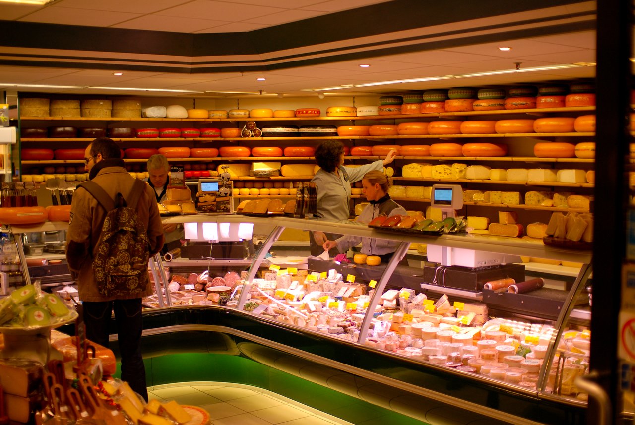 A cheese store with shelves full of cheese wheels.