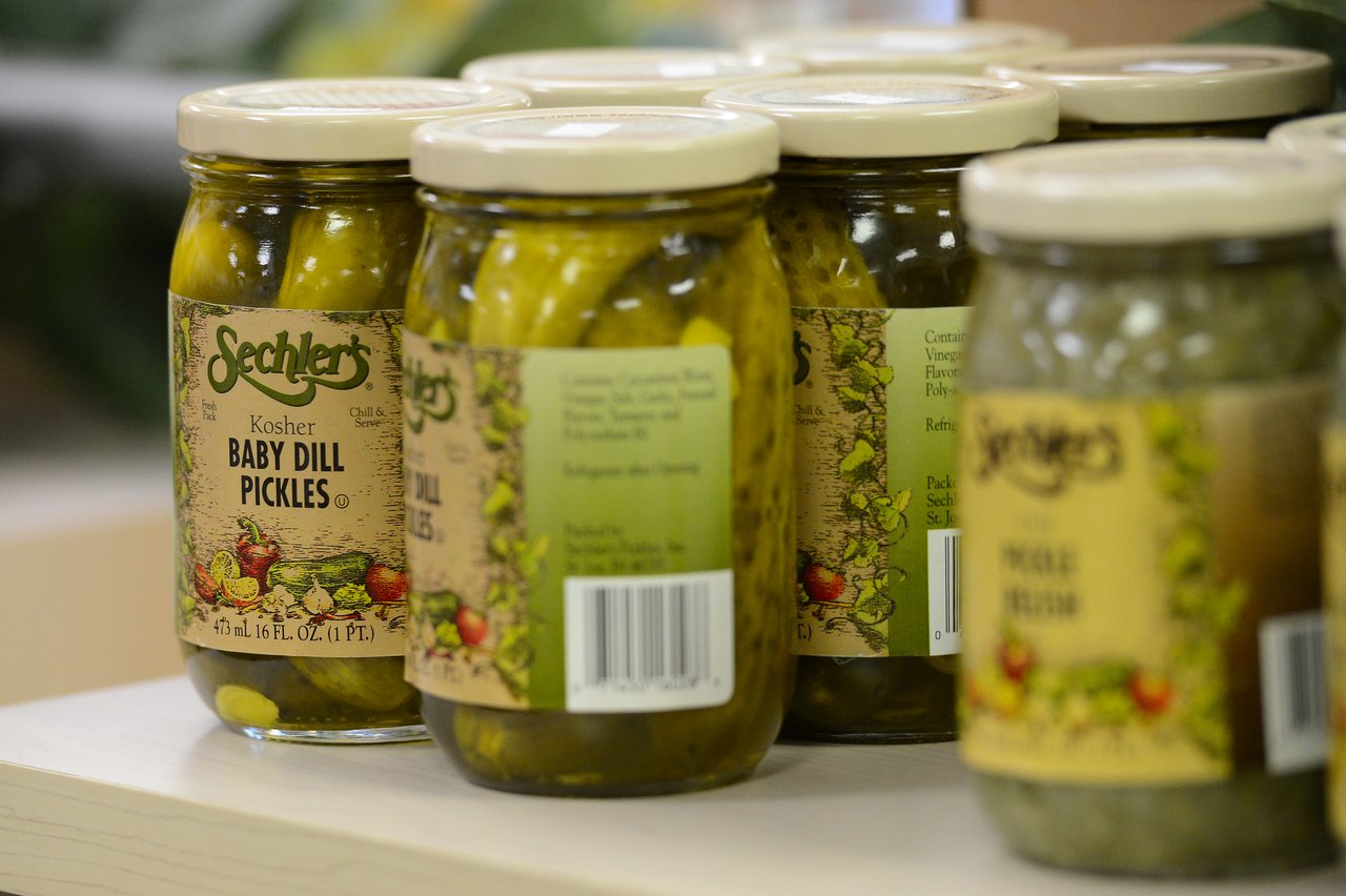 Jars of Sechler's baby dill pickles neatly arranged on a store shelf.