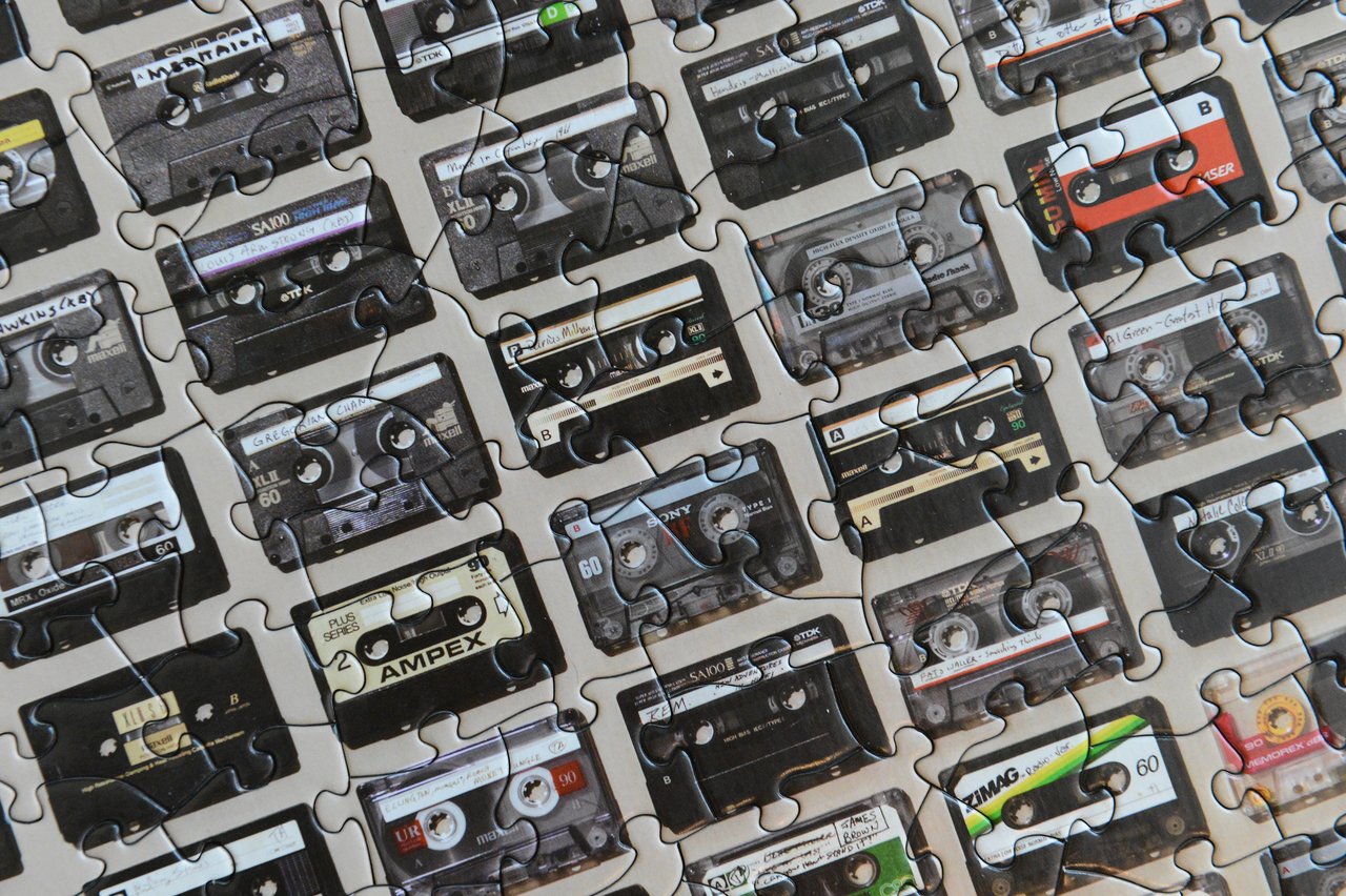 A completed jigsaw puzzle featuring an image of various cassette tapes arranged in rows.