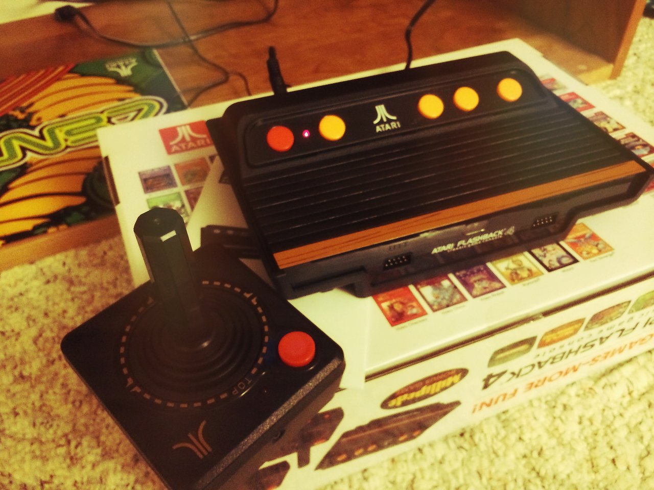 A retro Atari Flashback console with a joystick controller placed on its packaging box.