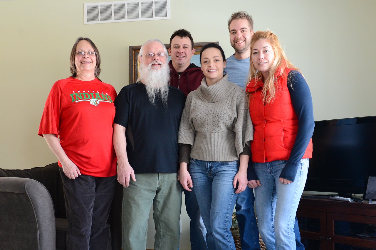 Six people stand close together indoors, smiling at the camera.