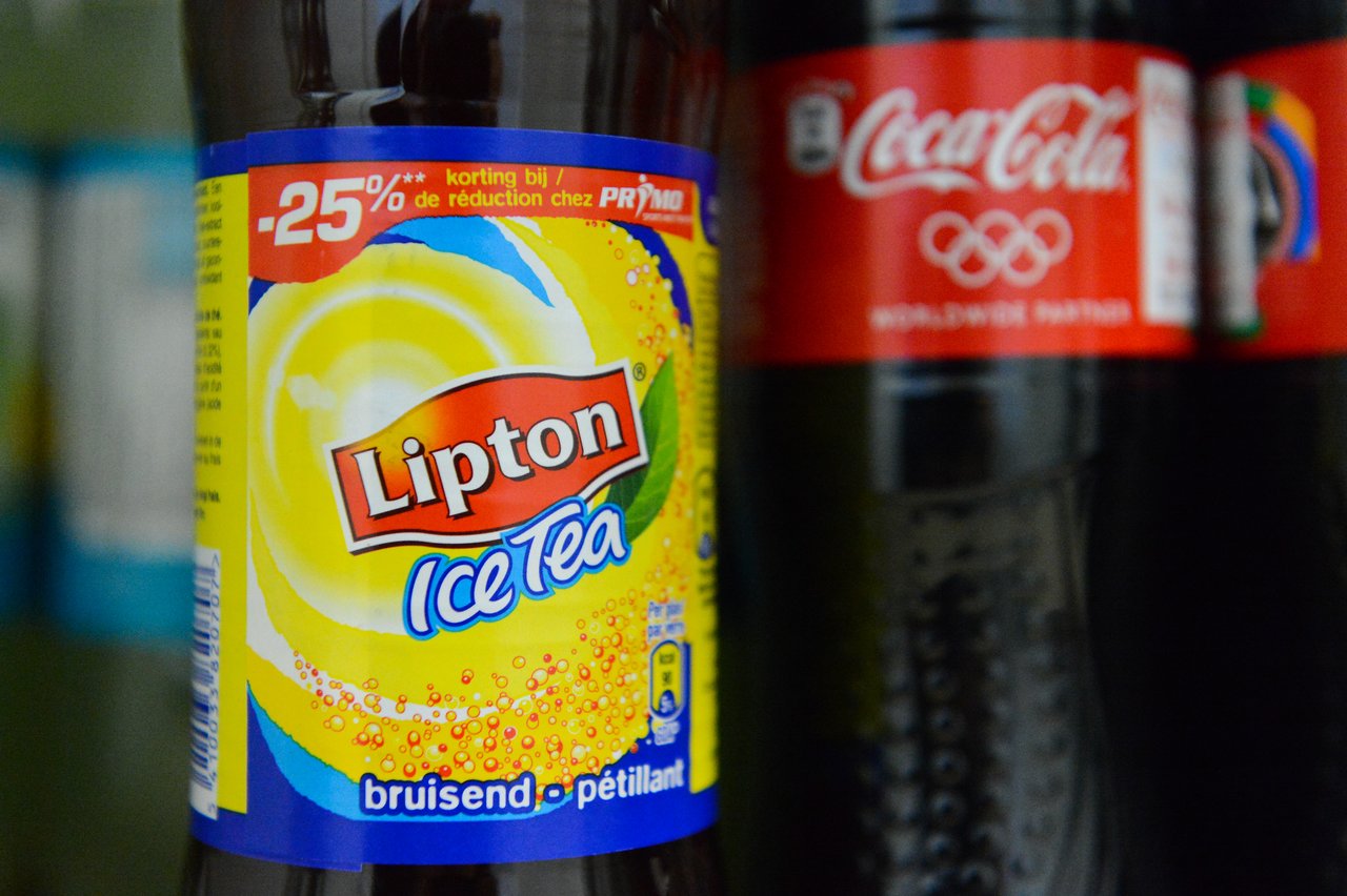 A bottle of Lipton carbonated iced tea with a discount label, next to a Coca-Cola bottle.