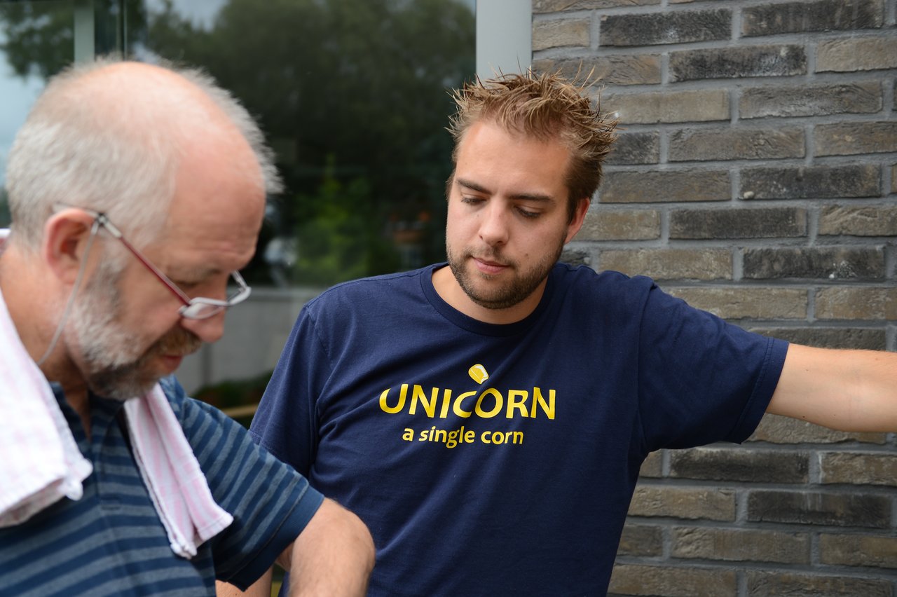 A man and his father stand outside, focused on something in front of them.