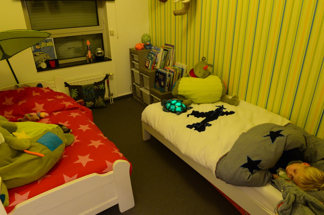 A child is sleeping in bed under a star-patterned blanket, with a glowing nightlight on the bed.