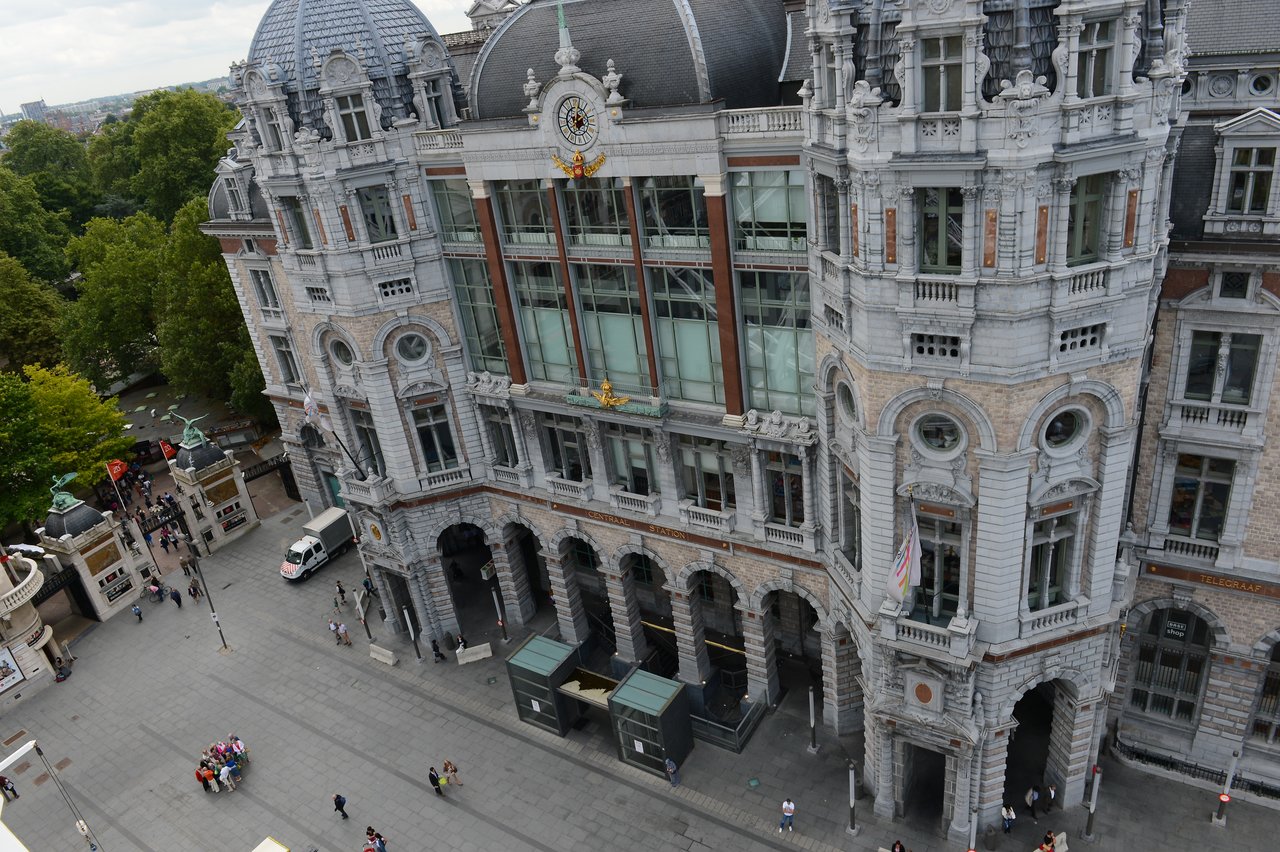 A high-angle view of a historic building with arched entrances and a clock, seen from a Ferris wheel.