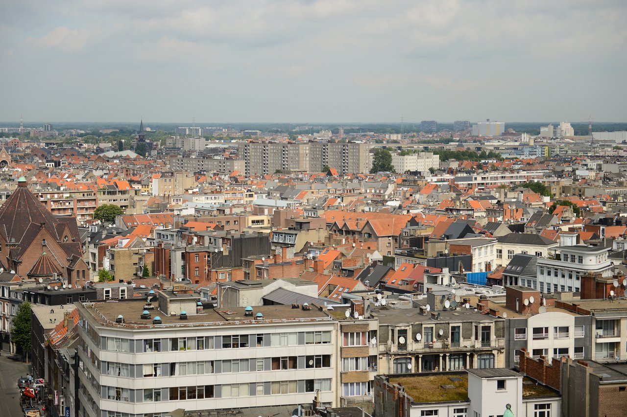 A high-angle view of a cityscape with many buildings and red rooftops, taken from a Ferris wheel.