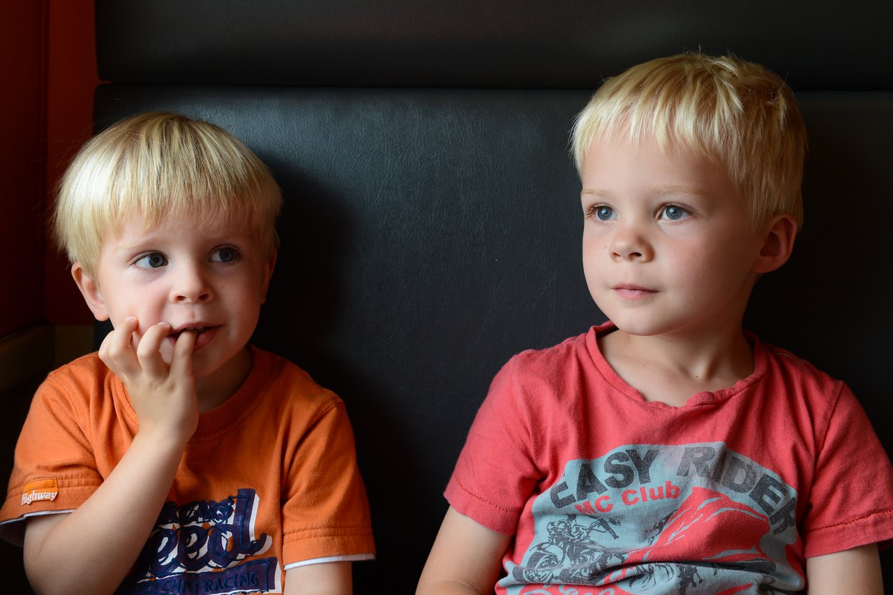 Two young children sit on a train, looking ahead.