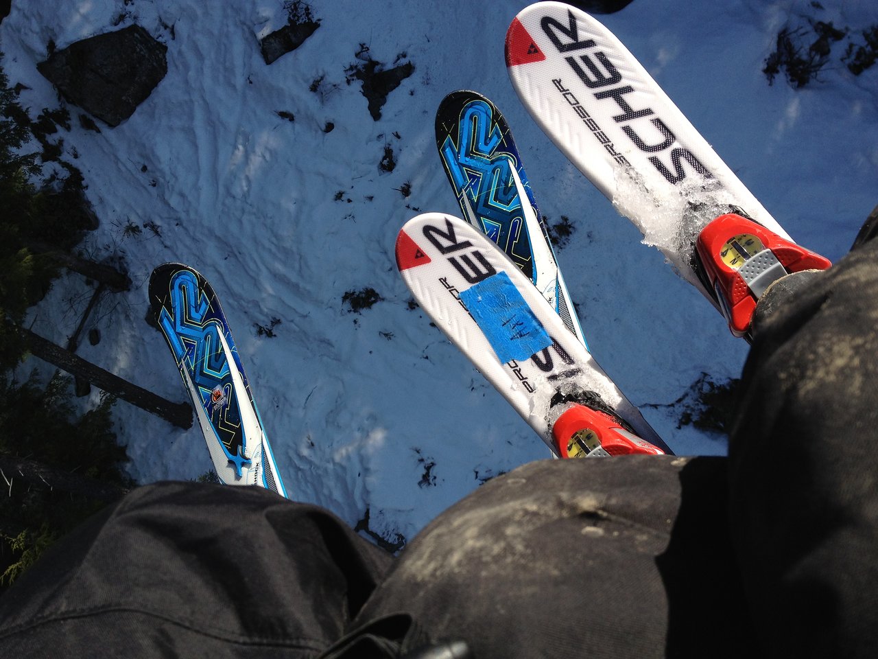 Two people riding a ski lift with their skis dangling above the snowy ground.