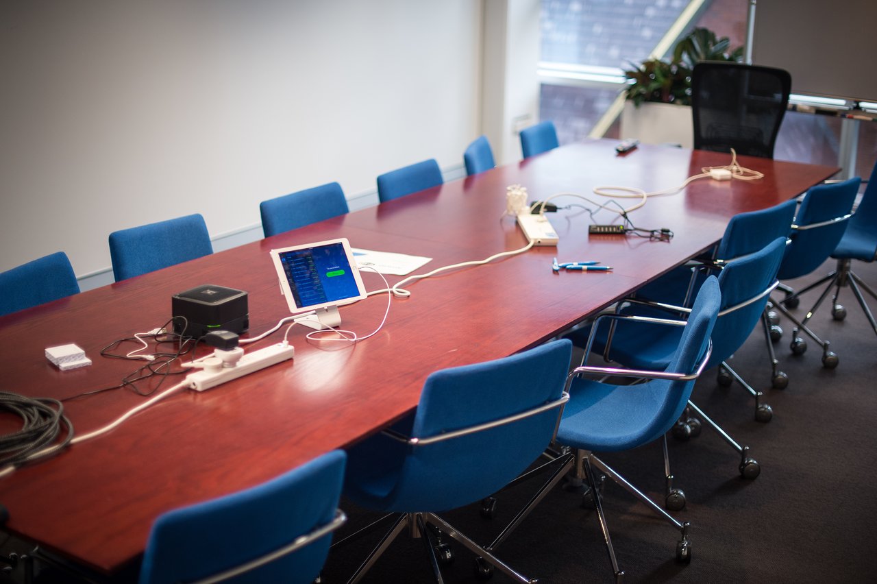 A conference room with a long brown table and blue office chairs.