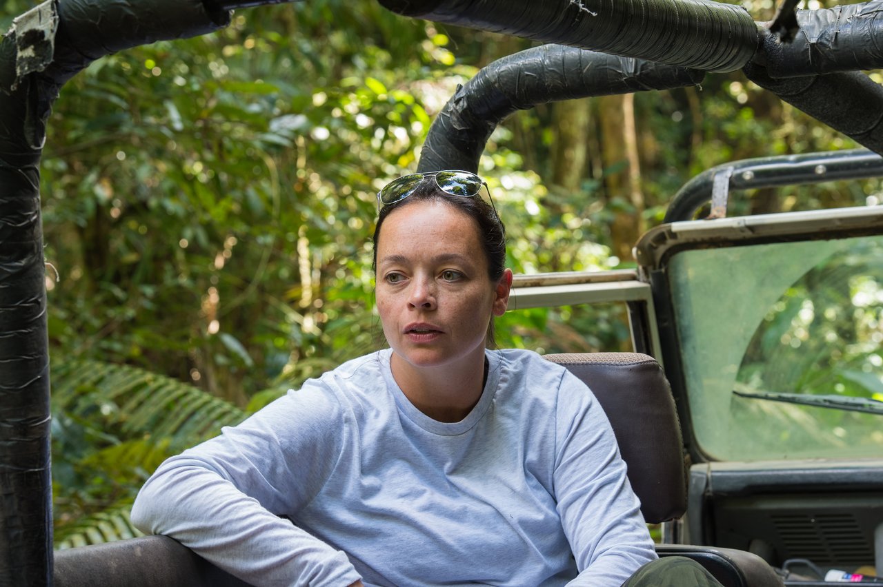 A woman sits in an open vehicle, looking ahead.