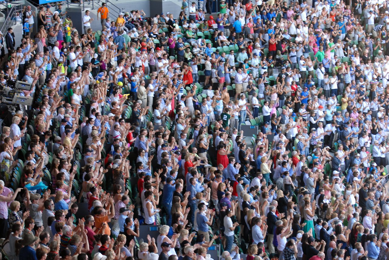 A large crowd of spectators stands and applauds during a match at the Australian Open 2012.