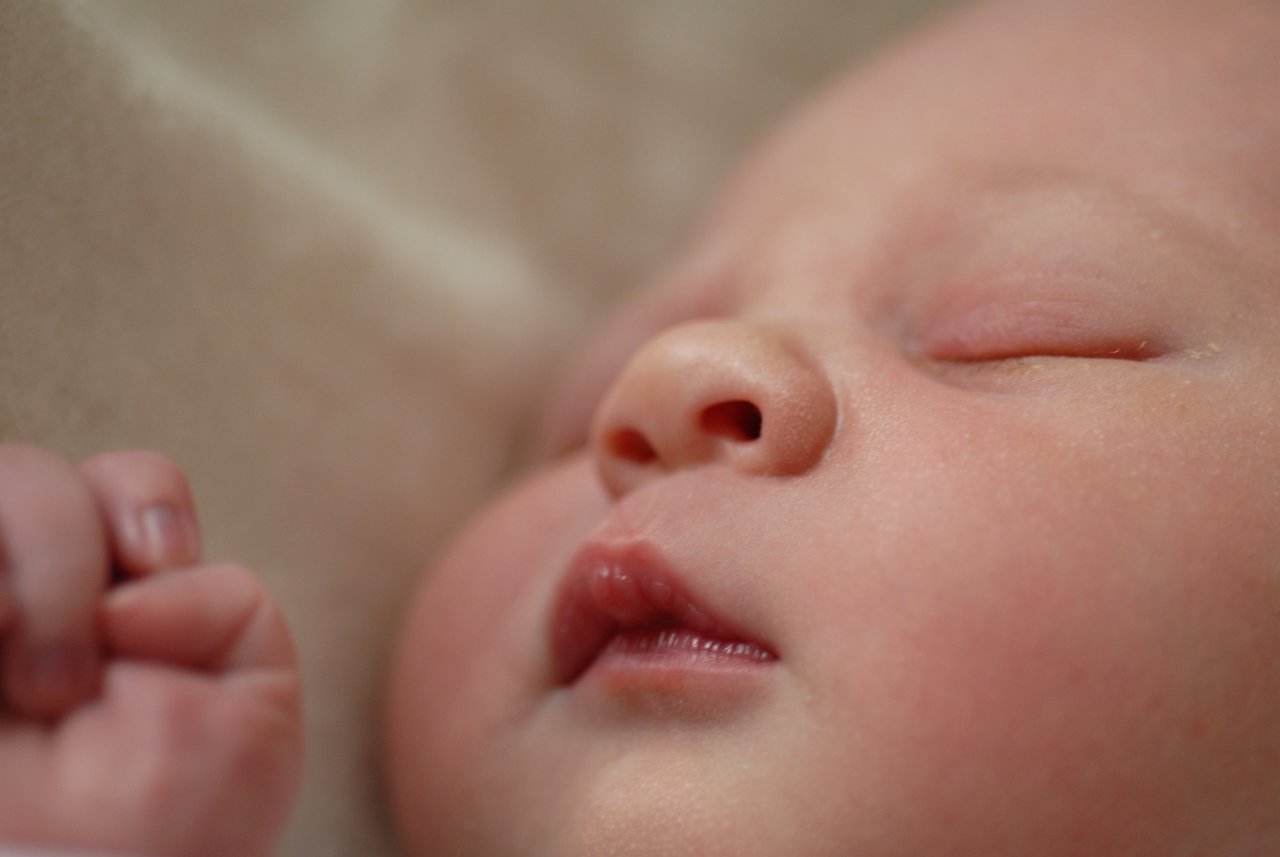 Close-up of a sleeping baby with eyes closed and a relaxed expression.