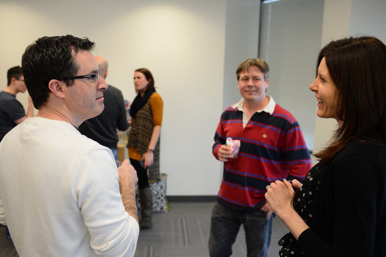 People chatting and smiling at a baby shower gathering in an indoor setting.