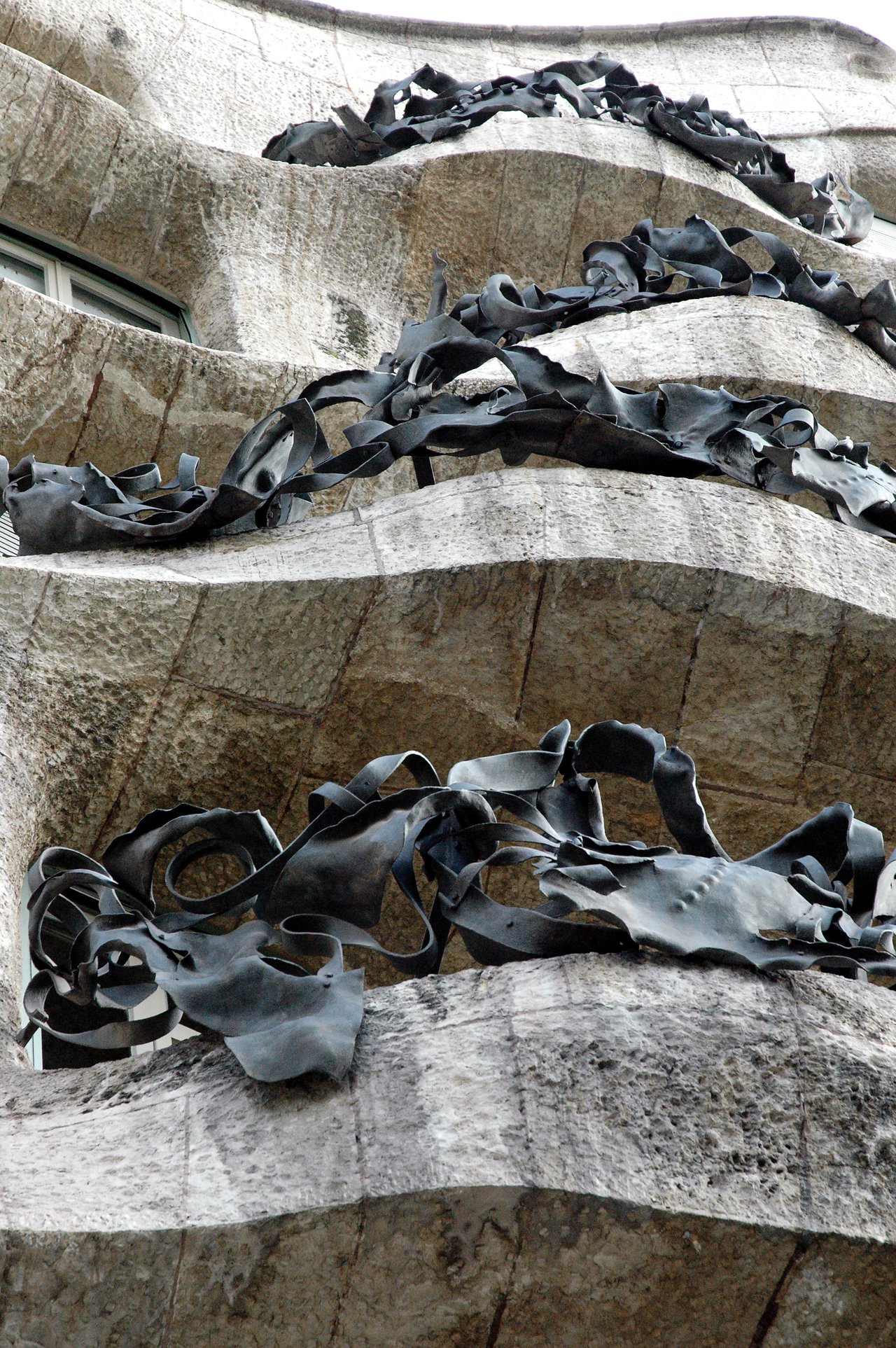 Close-up of La Pedrera's wavy stone balconies with intricate wrought iron railings in Barcelona, Spain.